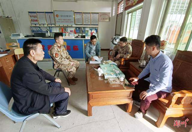 县人武部主要领导易定富在联饶镇下寨村了解应征青年报名情况。